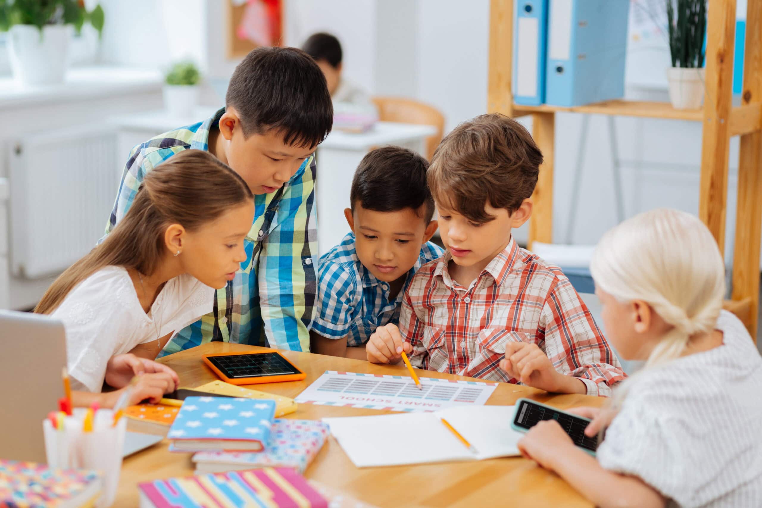 Friendship. Cute sweet company of classmates sitting in a classroom while doing homework